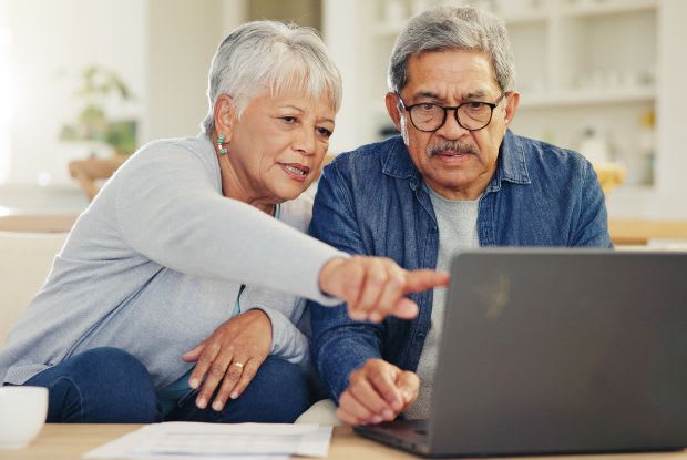 An elderly couple researching on a laptop