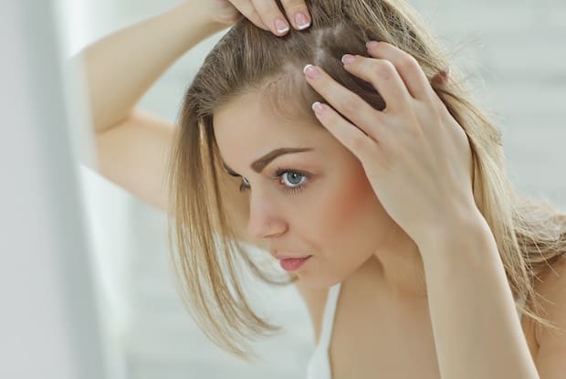 a woman examining her hair in the mirror