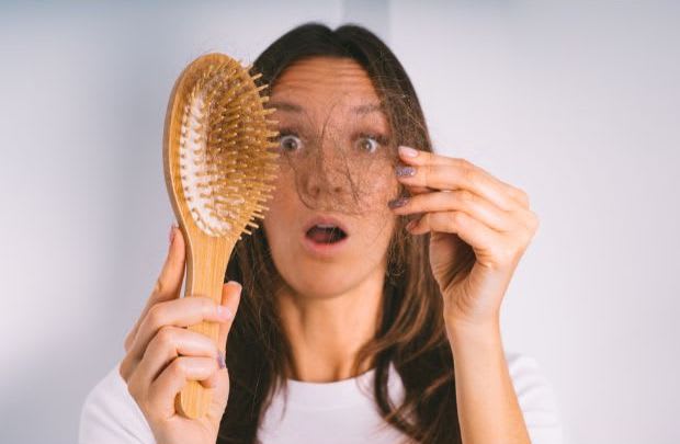 a shocked woman pulling hair out of a hairbrush