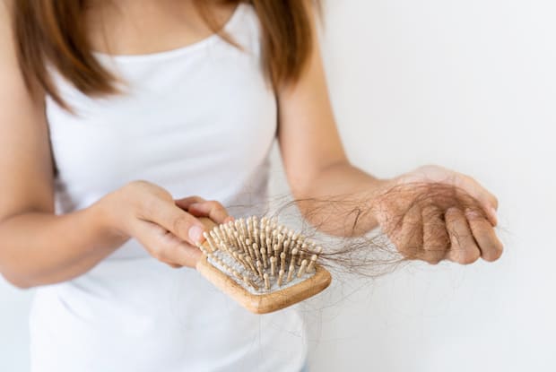 a woman pulling hair off a hairbrush