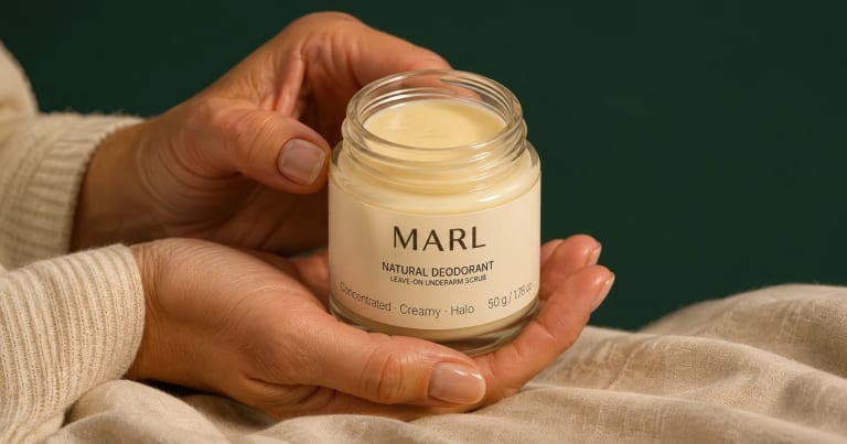 Hands in a cream knit jumper cradle an open jar of MARL natural deodorant