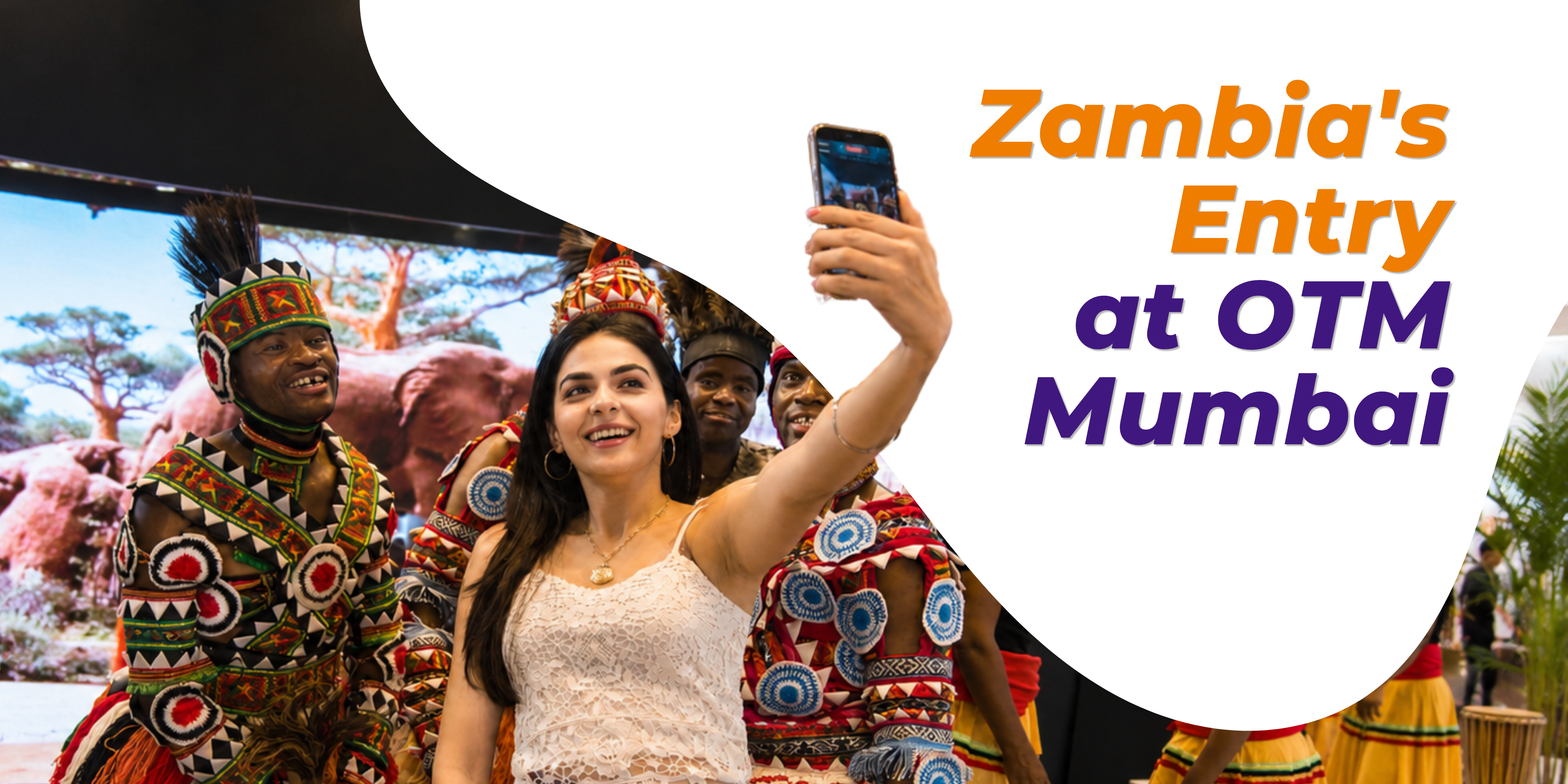 Visitor taking a selfie with traditional Zambian performers, showcasing Zambia's entry at OTM Mumbai