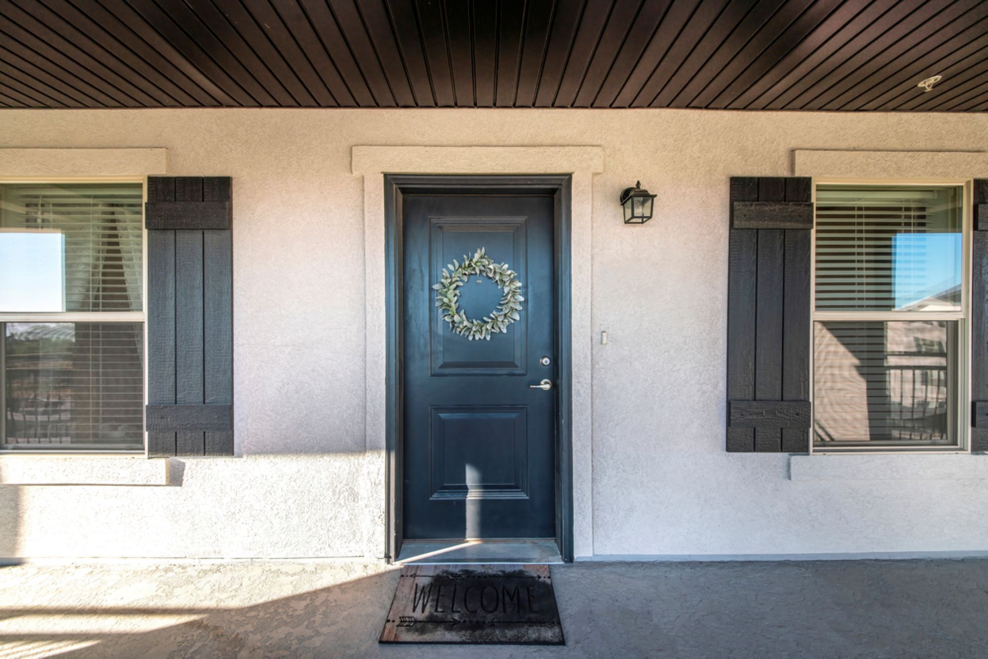 Front door exterior with dark wood plank ceiling and windows