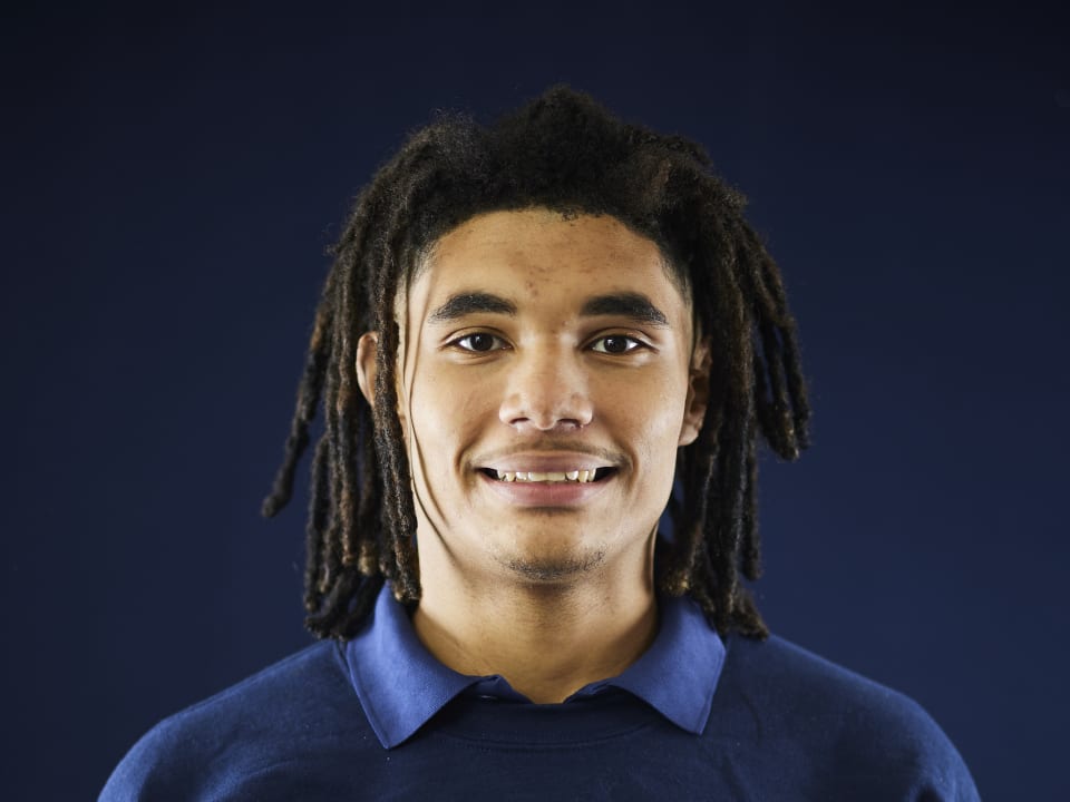 A student smiles warmly while wearing official SailFuture apparel during a portrait session.