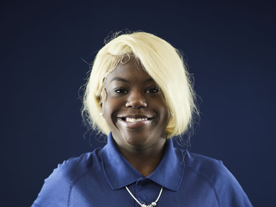 A student smiles warmly while wearing the SailFuture uniform polo shirt.