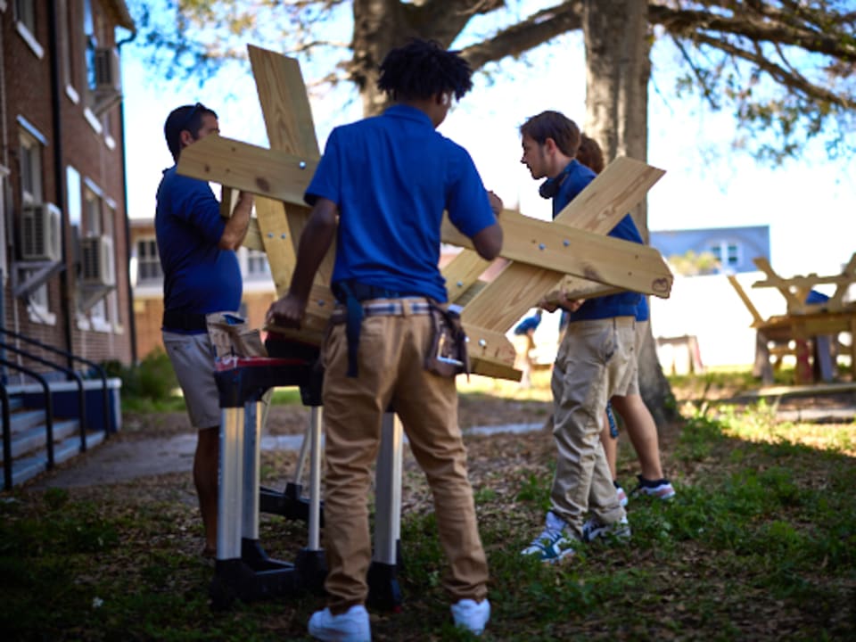 Students and an instructor collaborate on building a wooden picnic table during a Design Lab session.