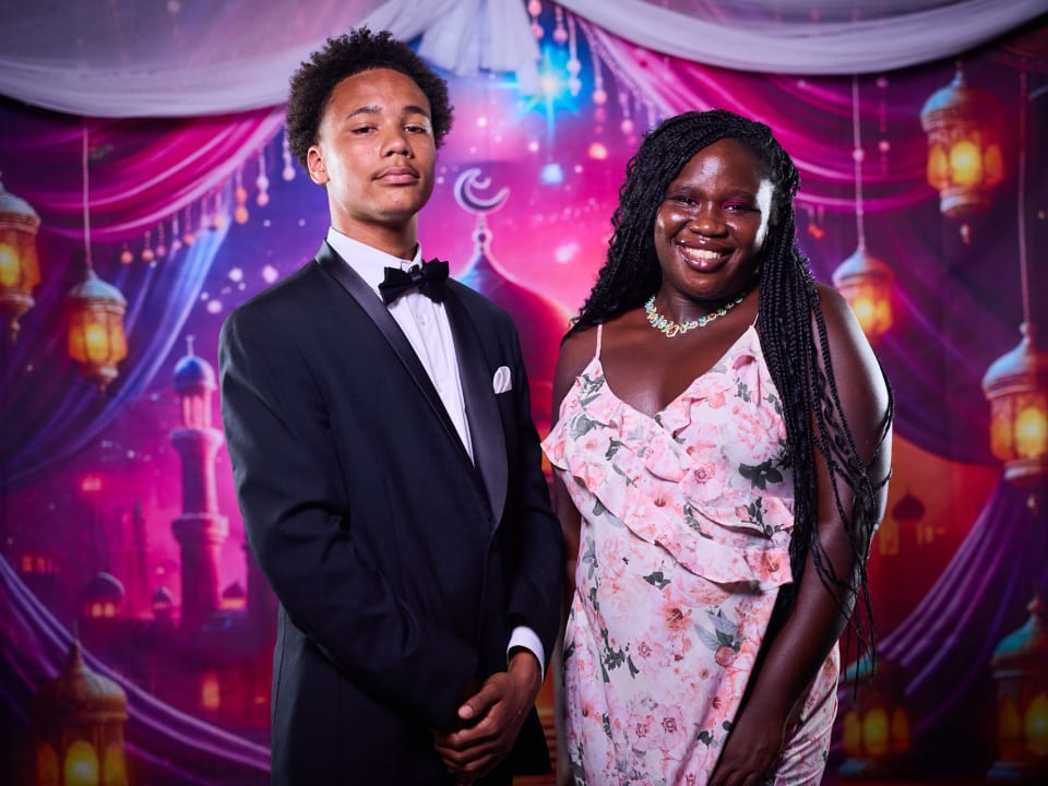 Students dressed up for the End of Term Bash celebrate together in front of a festive backdrop.