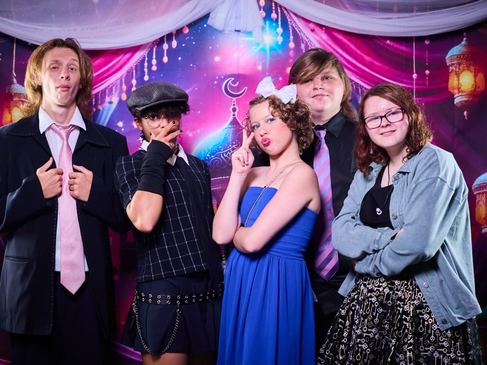 Students pose cheerfully in front of a themed backdrop during the End-of-Term Bash celebration.
