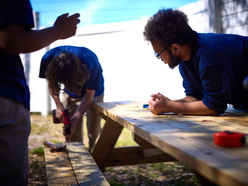 Students collaborate on a hands-on woodwork project outdoors during a Design Lab session.