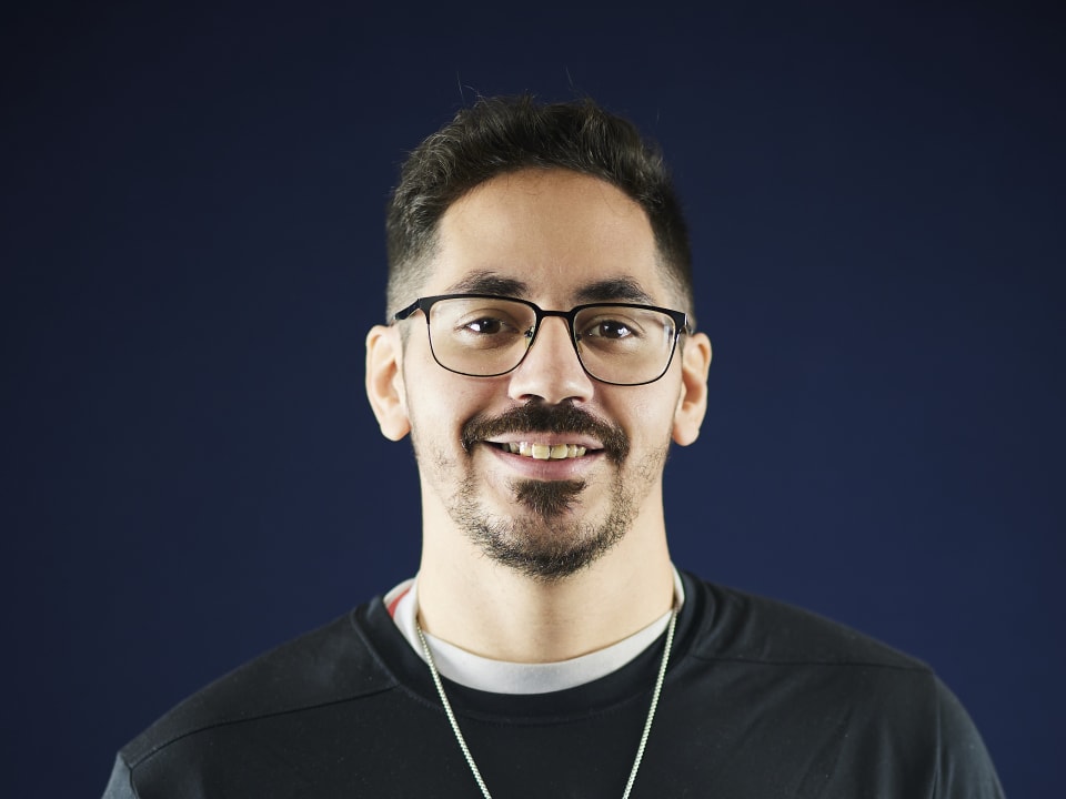 An instructor smiles for a portrait wearing a SailFuture branded shirt and a compass pendant.