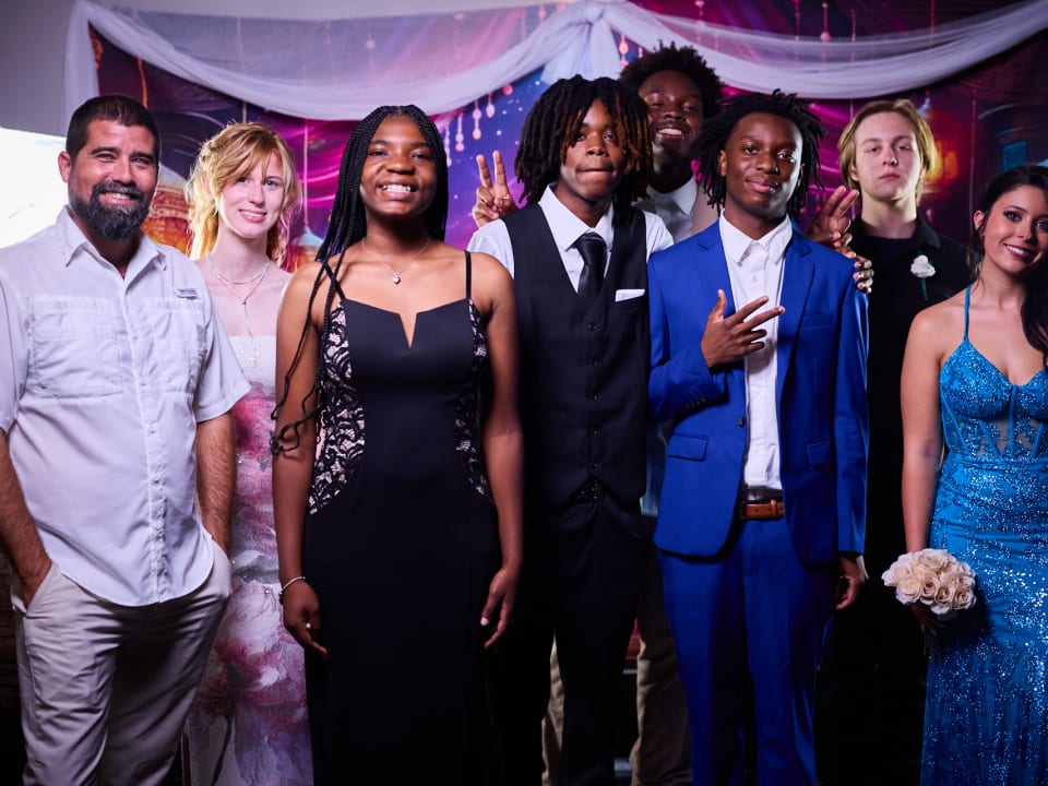 Students and staff pose together in formal attire to celebrate the end of the term.