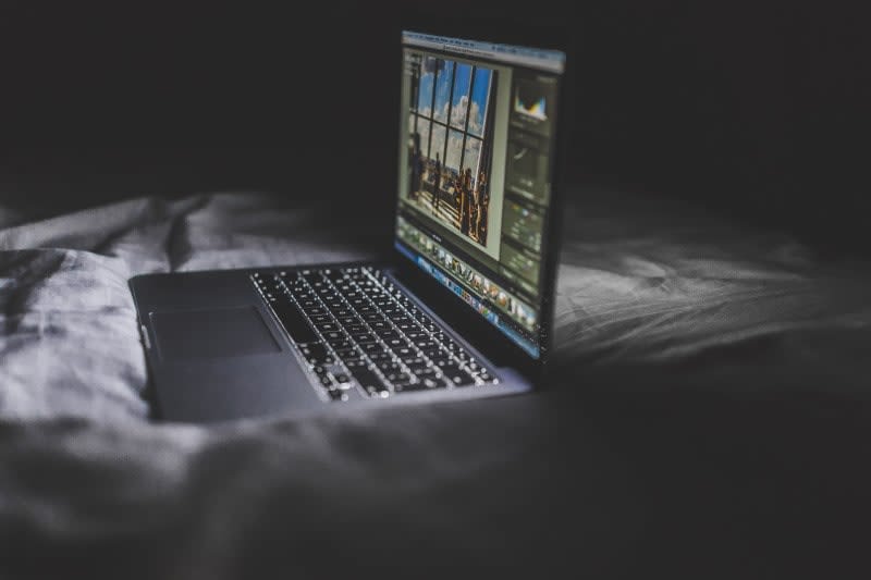Macbook on a bed in the dark