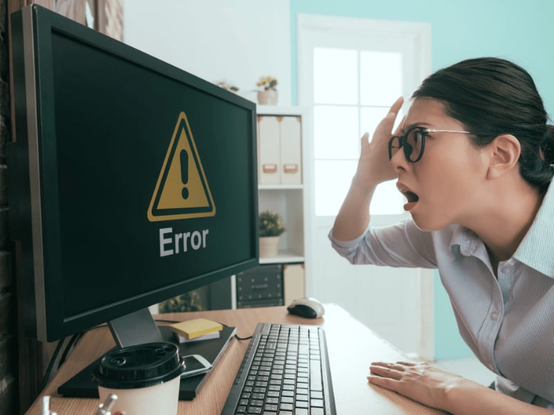Shocked woman looking at error screen on desktop