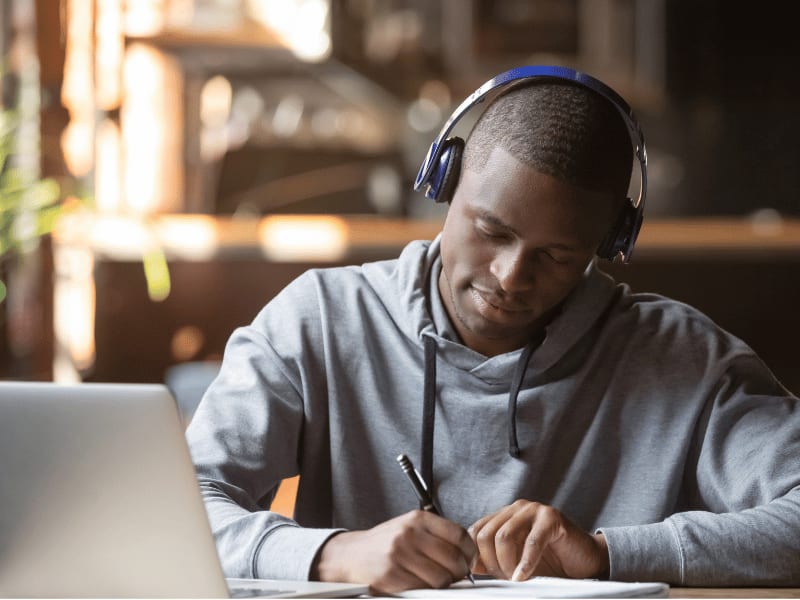 Man using Bluetooth headphones while studying on a laptop
