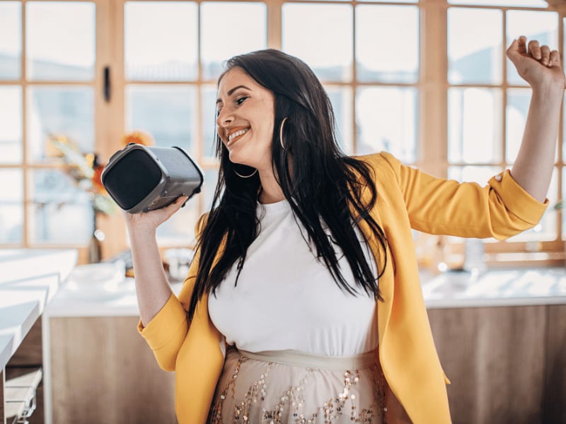 Woman enjoying music from a portable Bluetooth speaker at home