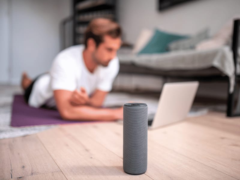 Man lying on the floor with laptop and Bluetooth speaker in foreground