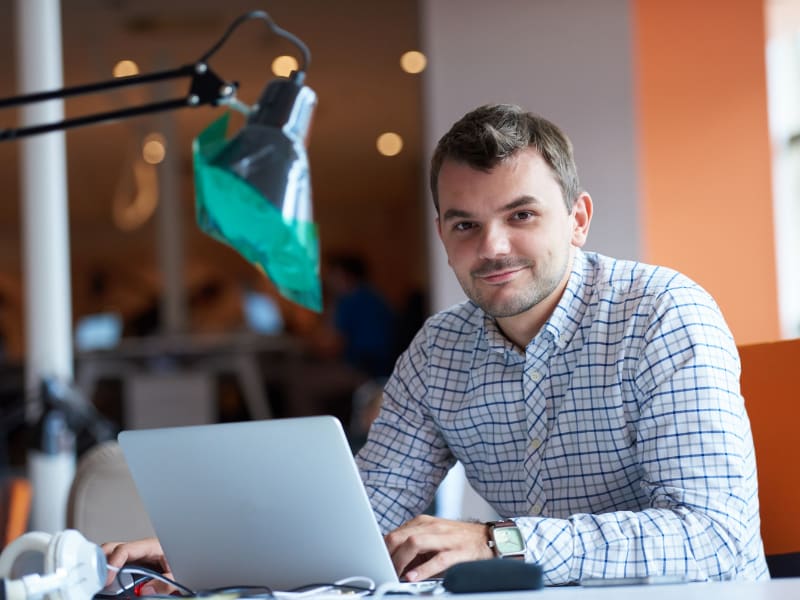 Smiling professional working on a laptop after resolving missing desktop icon problems