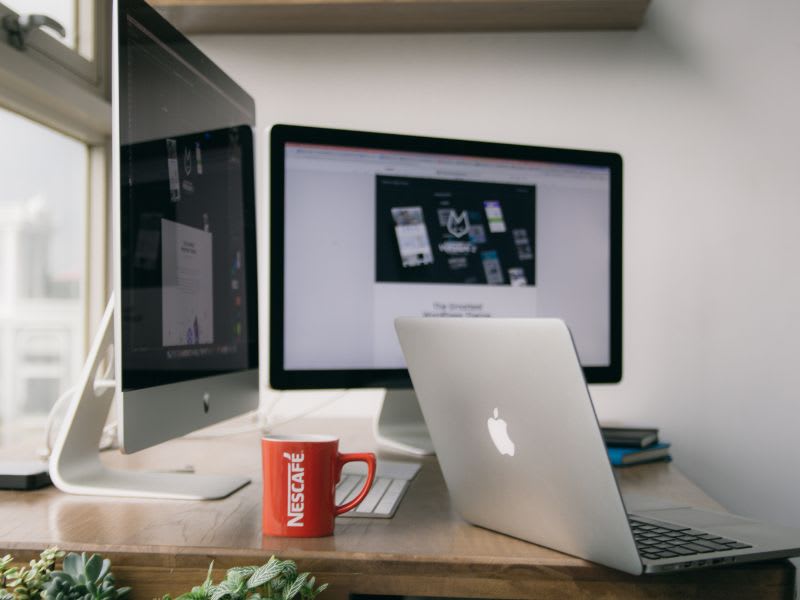 MacBook and desktop monitor displaying a webpage, representing troubleshooting boot errors on a Mac.