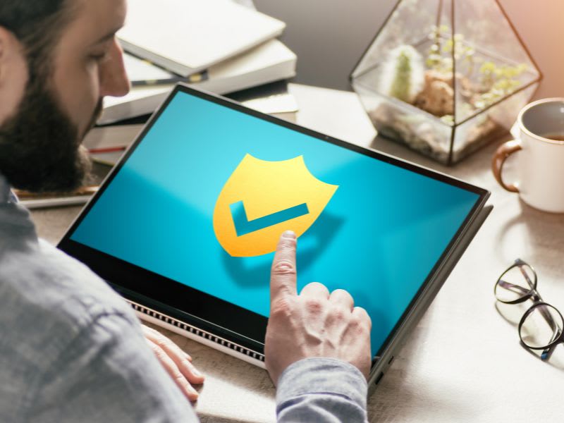 Man using antivirus software on laptop to protect against crashes and malware and provide computer keeps crashing solutions.