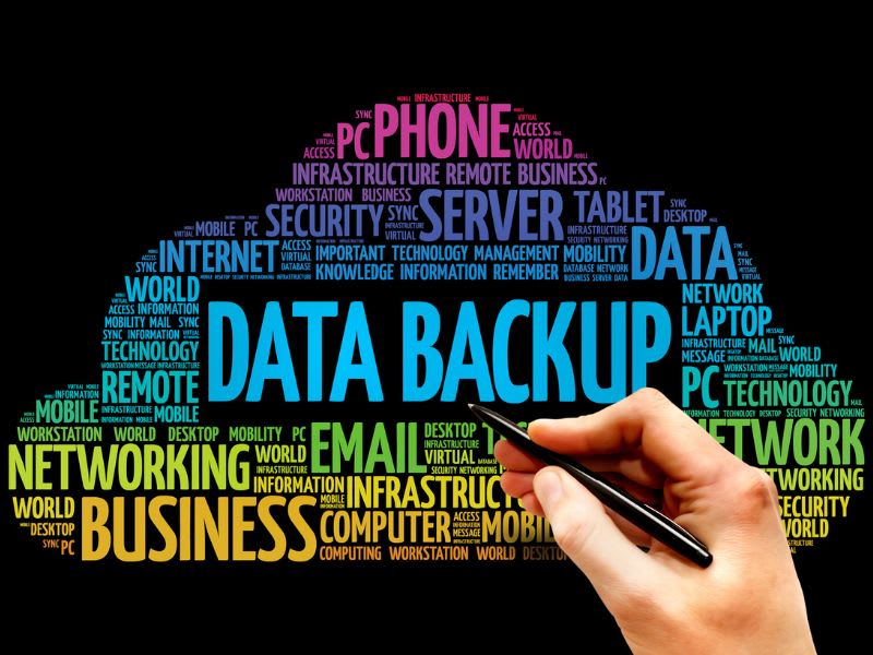 Hand writing on digital word cloud with the phrase “Data Backup” surrounded by related tech terms