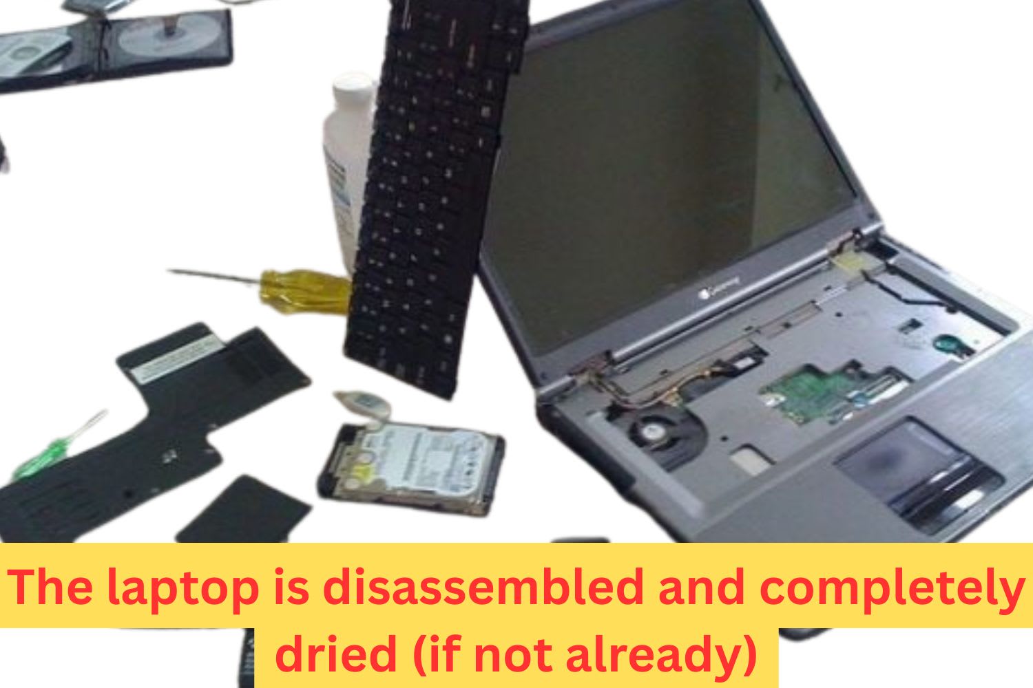 Old laptop completely disassembled on the floor with keyboard, hard drive, battery, and internal components laid out for water damage inspection.