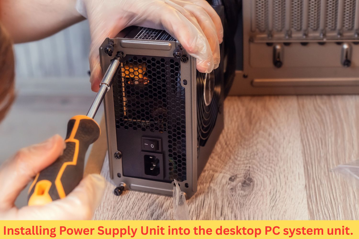 Technician installing a power supply unit (PSU) into a desktop PC case using a screwdriver while wearing protective gloves