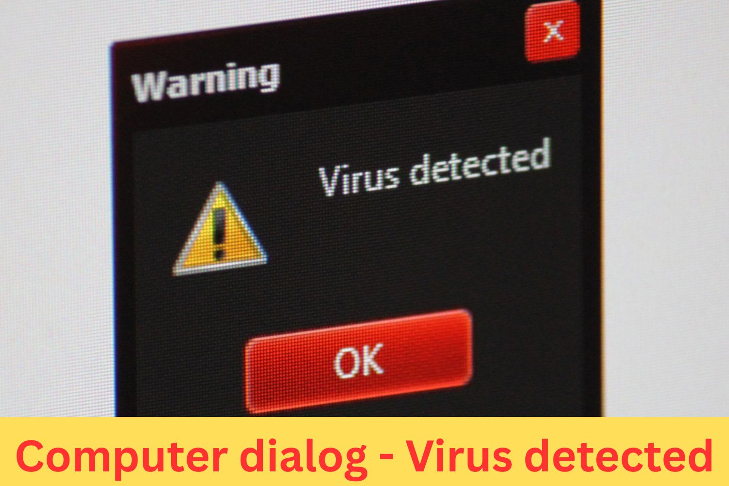 Close-up of a computer screen showing a virus detected warning dialog with alert icon and red OK button