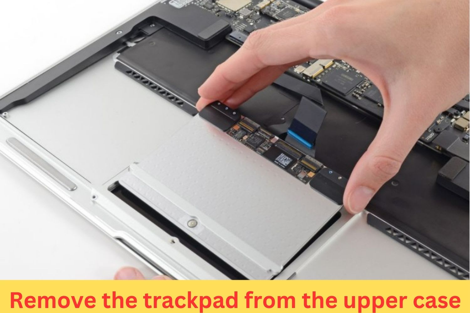 Hand removing the trackpad from a MacBook upper case during laptop repair or replacement process