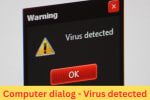 Close-up of a computer screen showing a virus detected warning dialog with alert icon and red OK button