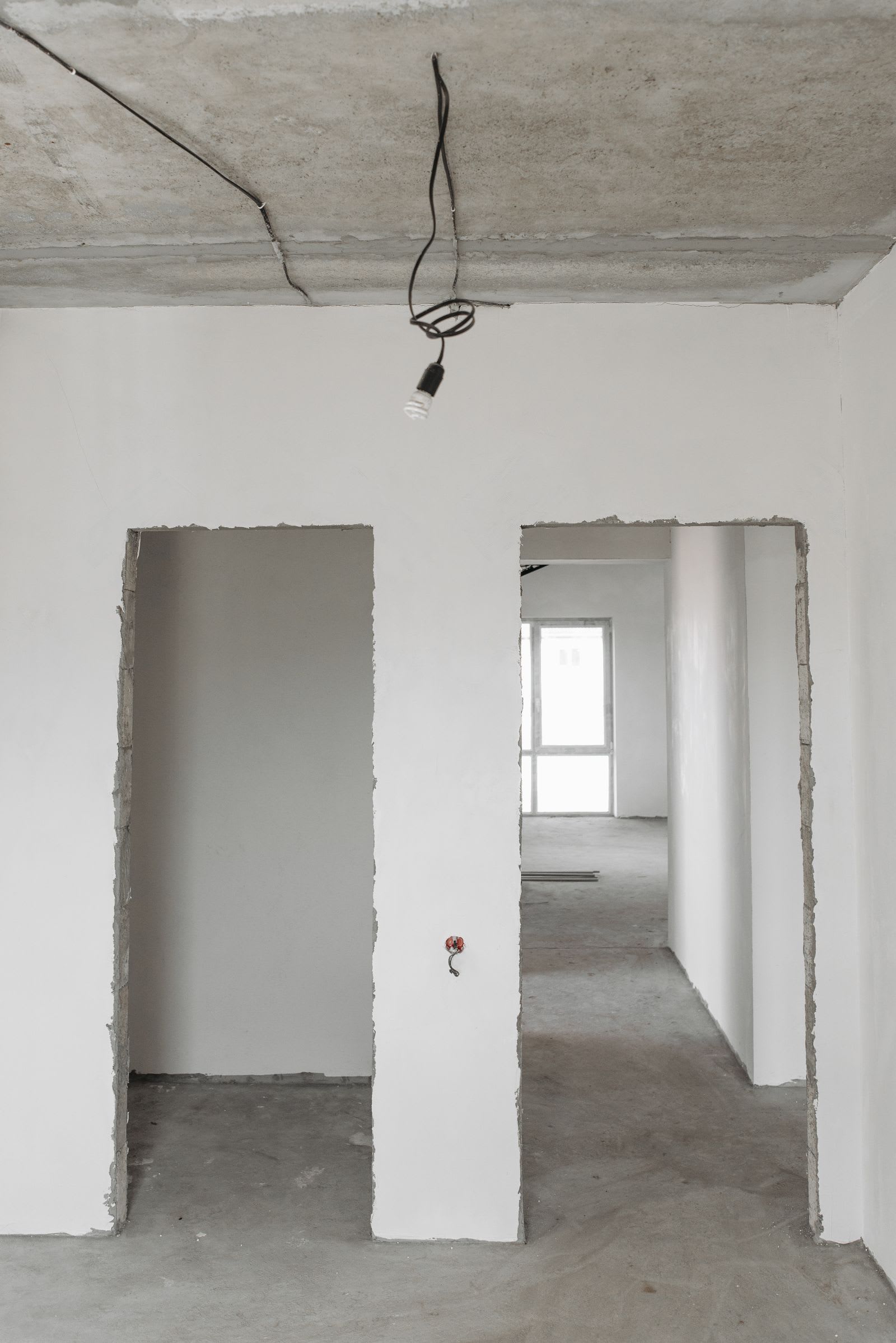 Rohbau-Innenraum mit weiß verputzten Wänden und Betondecke