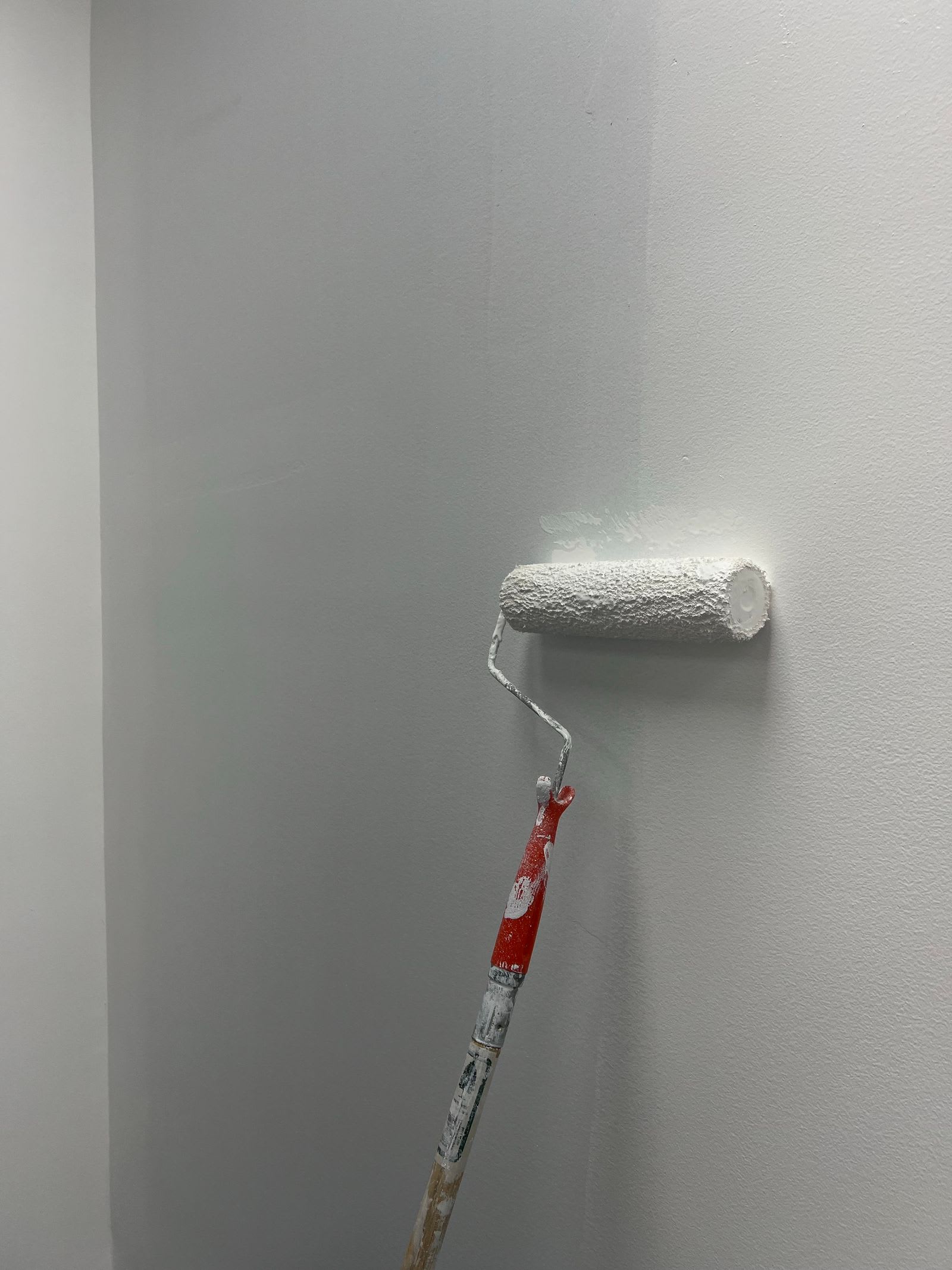 Strukturwalze trägt weiße Grundierung auf eine Innenwand auf