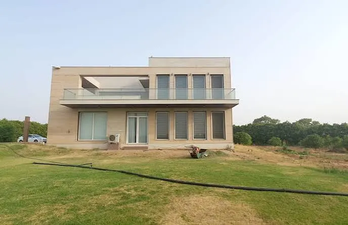 "Modern luxury house for sale in Gurgaon featuring a contemporary two-story design, spacious lawn, glass balcony, and premium residential surroundings."