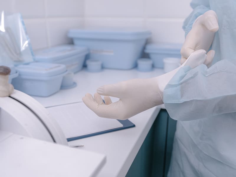 Health worker putting on sterile gloves in a clean manufacturing environment before handling a sterile-packed device