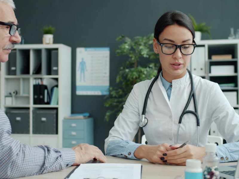 Medical professional discussing treatment options with an older male patient in a modern office setting