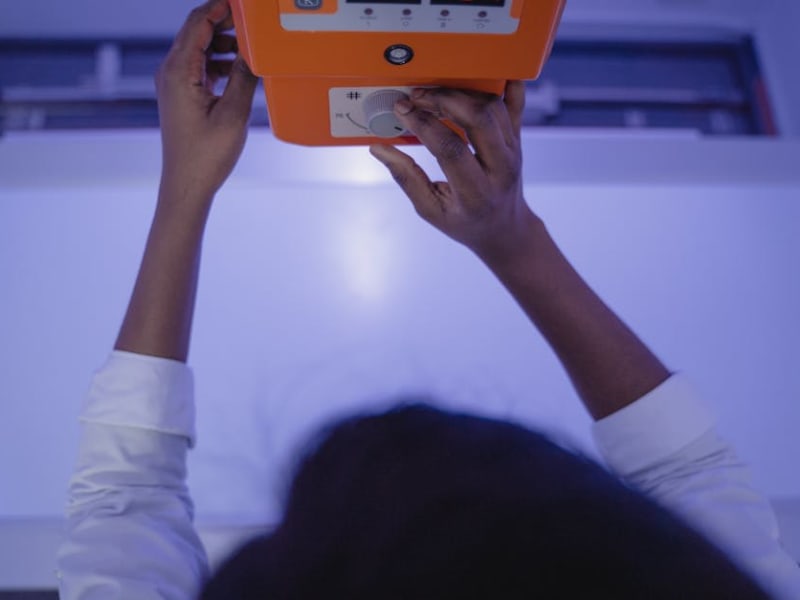 A medical professional adjusting an X-ray machine in a clinic setting.