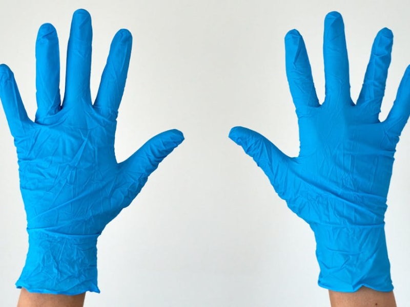A pair of hands wearing blue latex gloves for hygienic protection and safety.