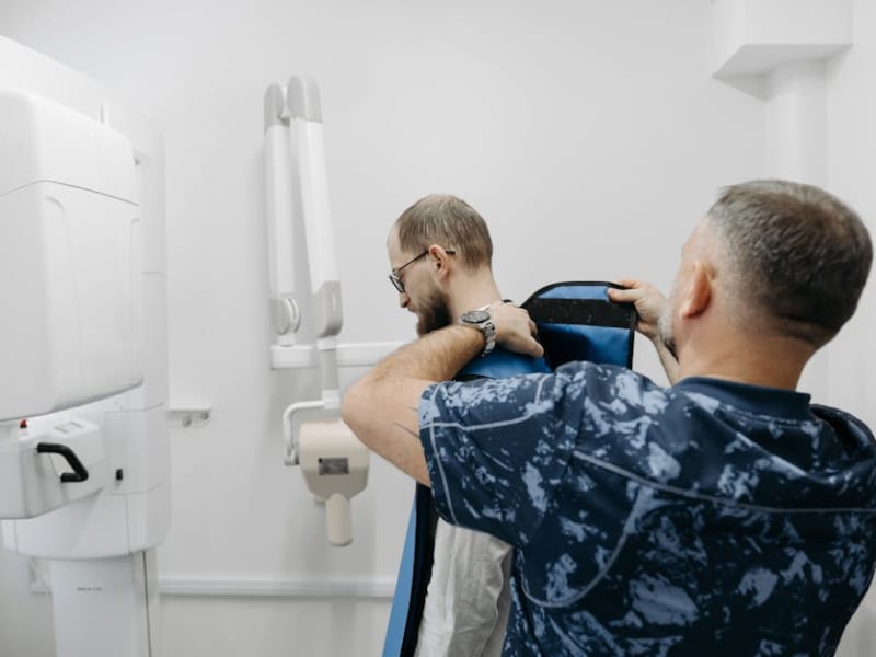 A healthcare professional helps a patient prepare for an X-ray examination in a modern clinic.