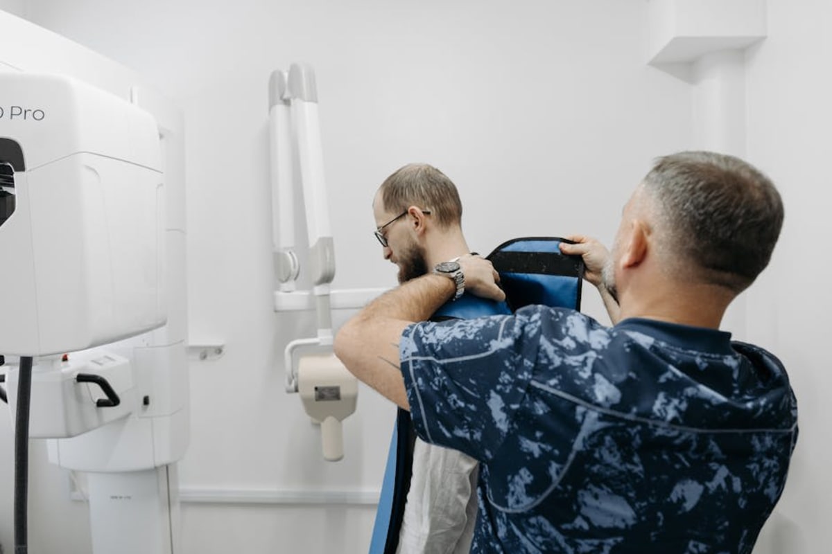 A healthcare professional helps a patient prepare for an X-ray examination in a modern clinic.