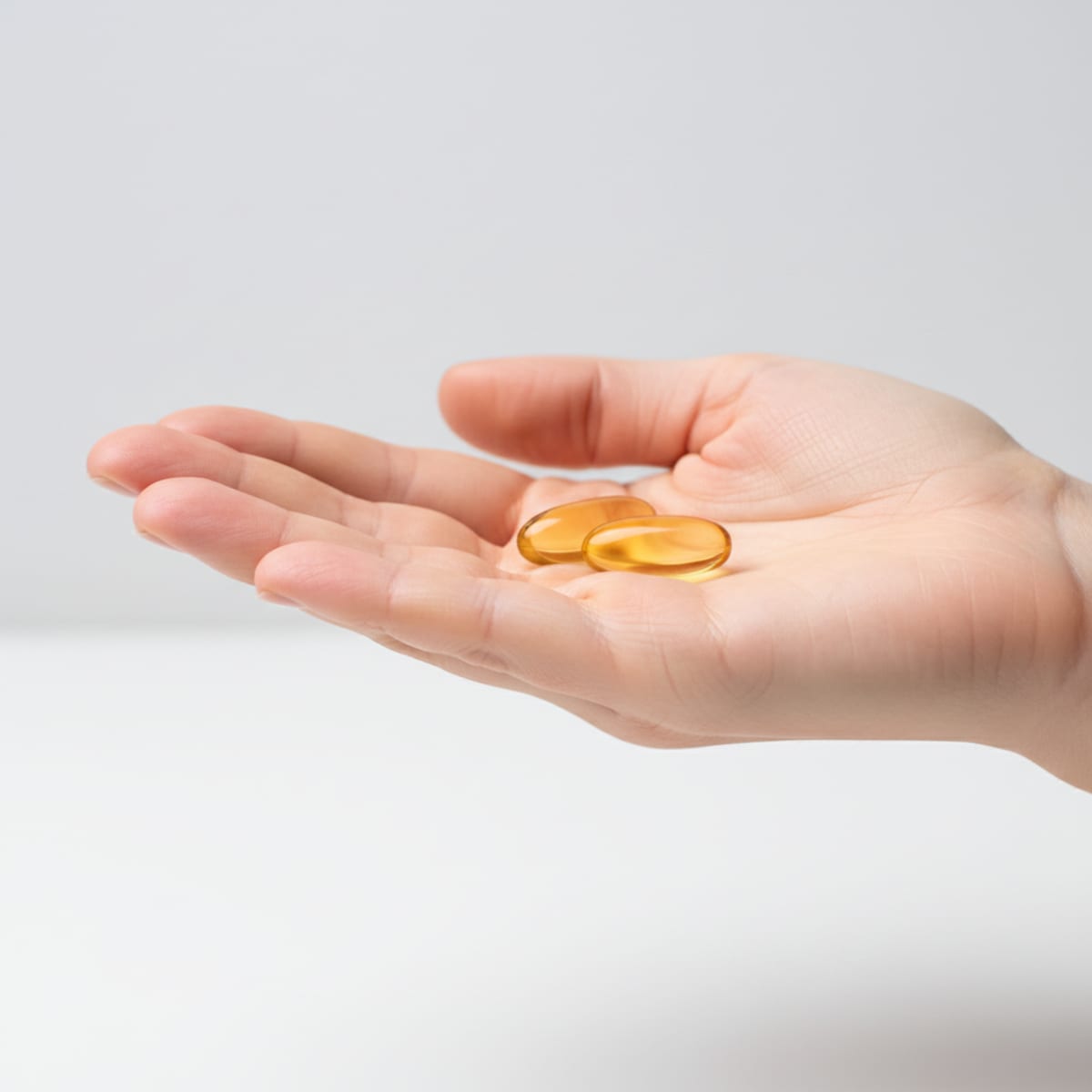 An open hand holding the two daily SURIA softgel capsules — the real 1000mg dose