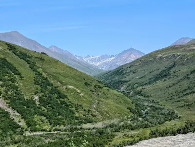 Green valleys leading up to still snow covered mountains
