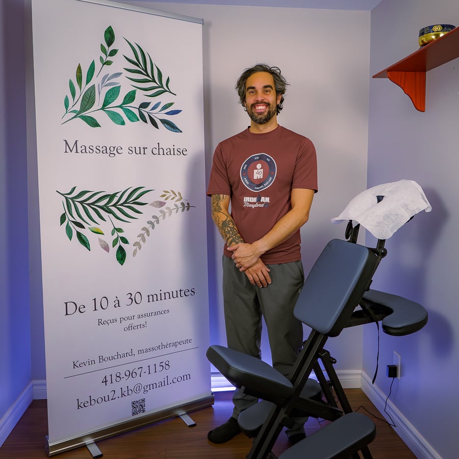 Portrait corporatif d'un massothérapeute posant avec une chaise de massage
