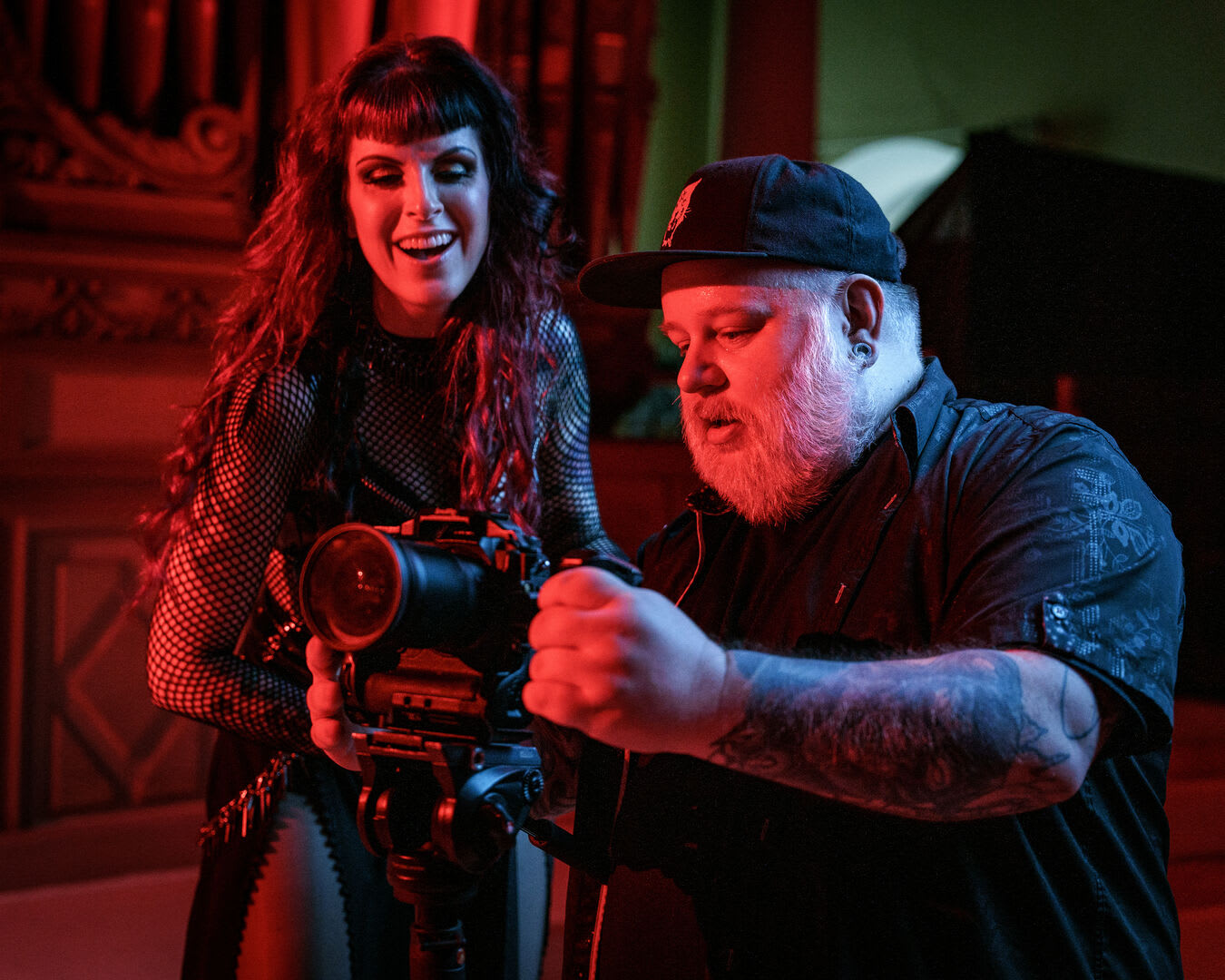 La chanteuse de Forgotten Tales et le vidéaste vérifient une prise sur la caméra, sous une lumière rouge intense