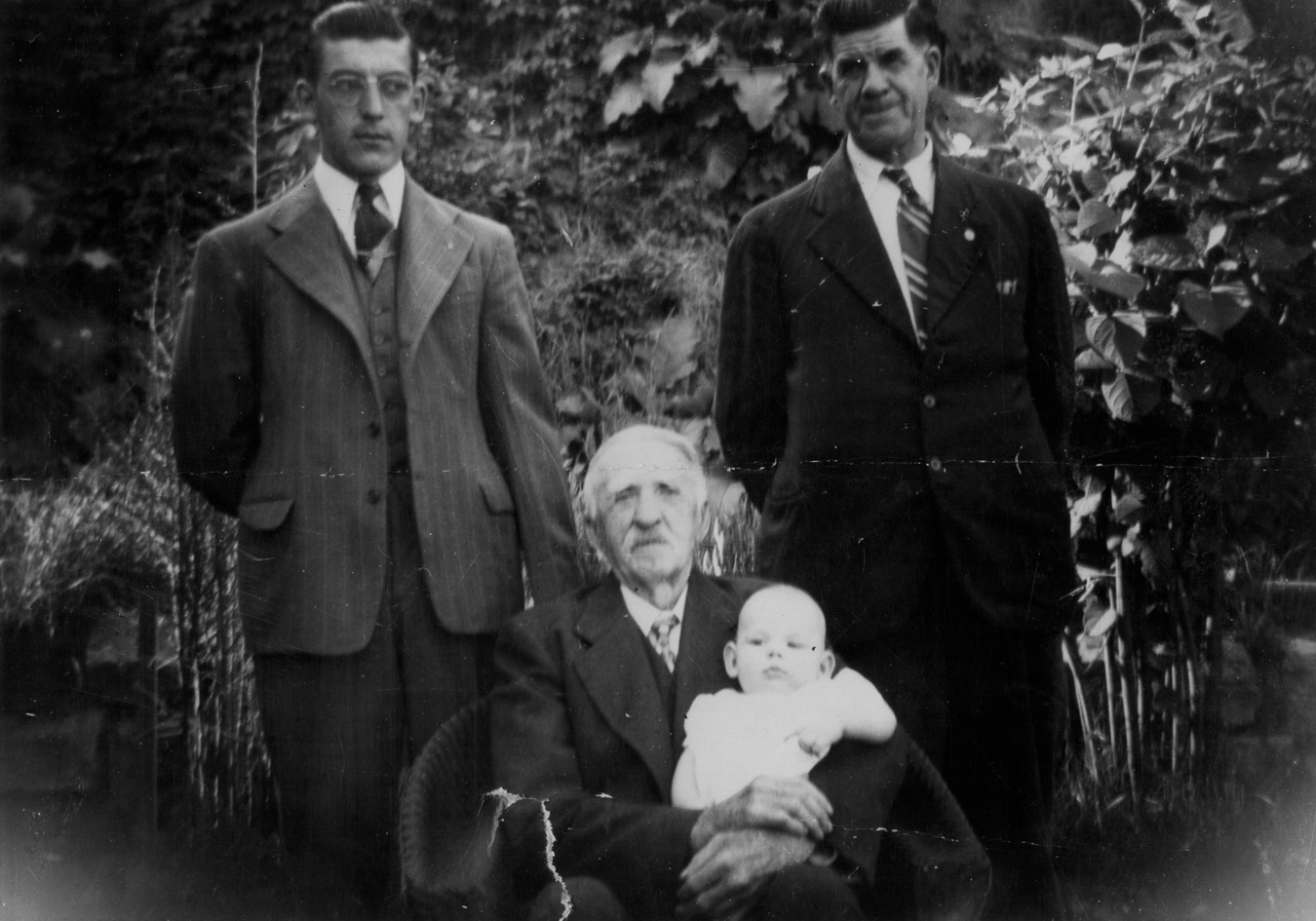 Before, old damaged photo of four men from different generations