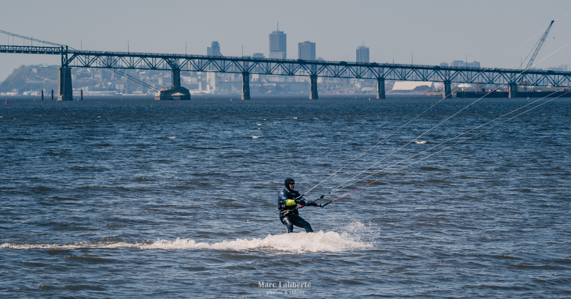 Un kitesurfeur sillonne le fleuve Saint-Laurent, avec la silhouette majestueuse de Québec en toile de fond.