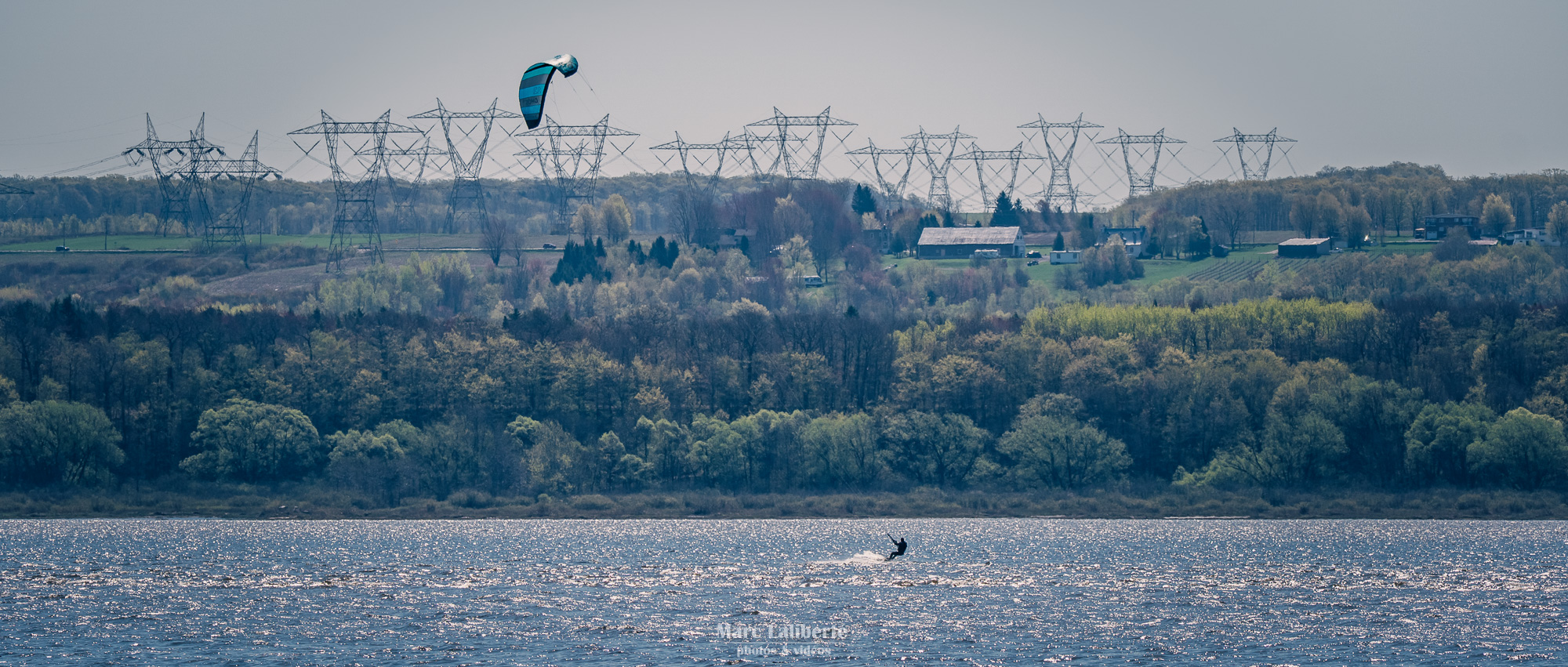 Un sportif navigue en kitesurf le long du Saint-Laurent, avec la vue imprenable sur l'île d'Orléans.