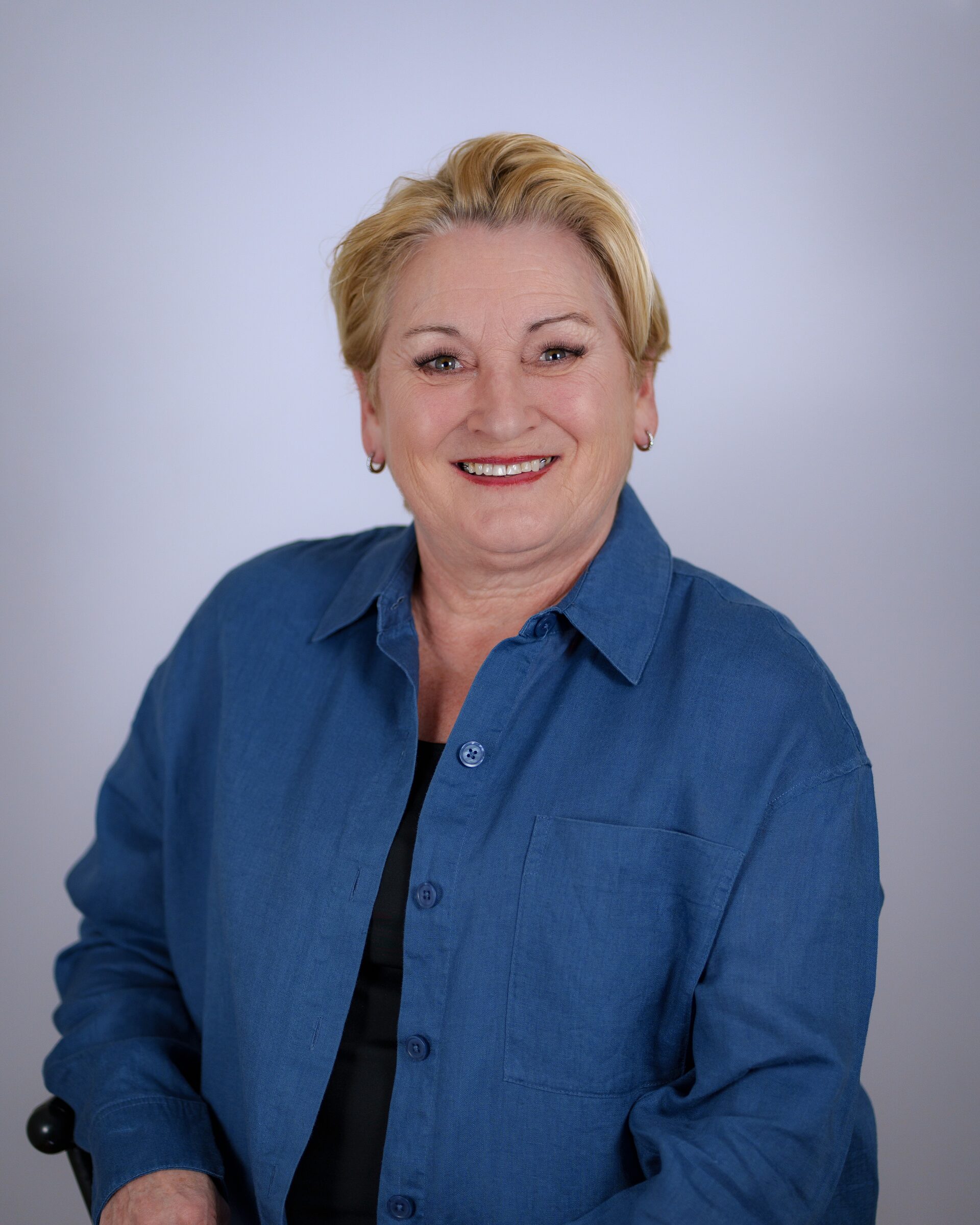 Portrait d'une femme aux cheveux blonds courts portant une chemise bleue en studio