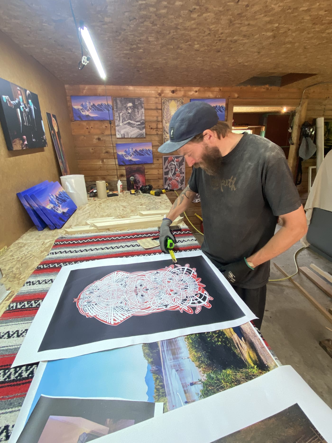Measuring a fine-art print in the WinPrint shop, finished canvases on the wall behind