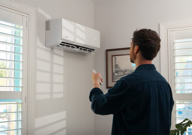 Man using the MRCOOL® Comfort App to control the DIY® Select air handler in a living room.