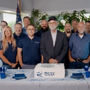 MRCOOL team of employees gathered around a company celebration cake marking continued growth and expansion