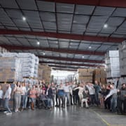 Group of warehouse employees gathered together inside a large distribution warehouse